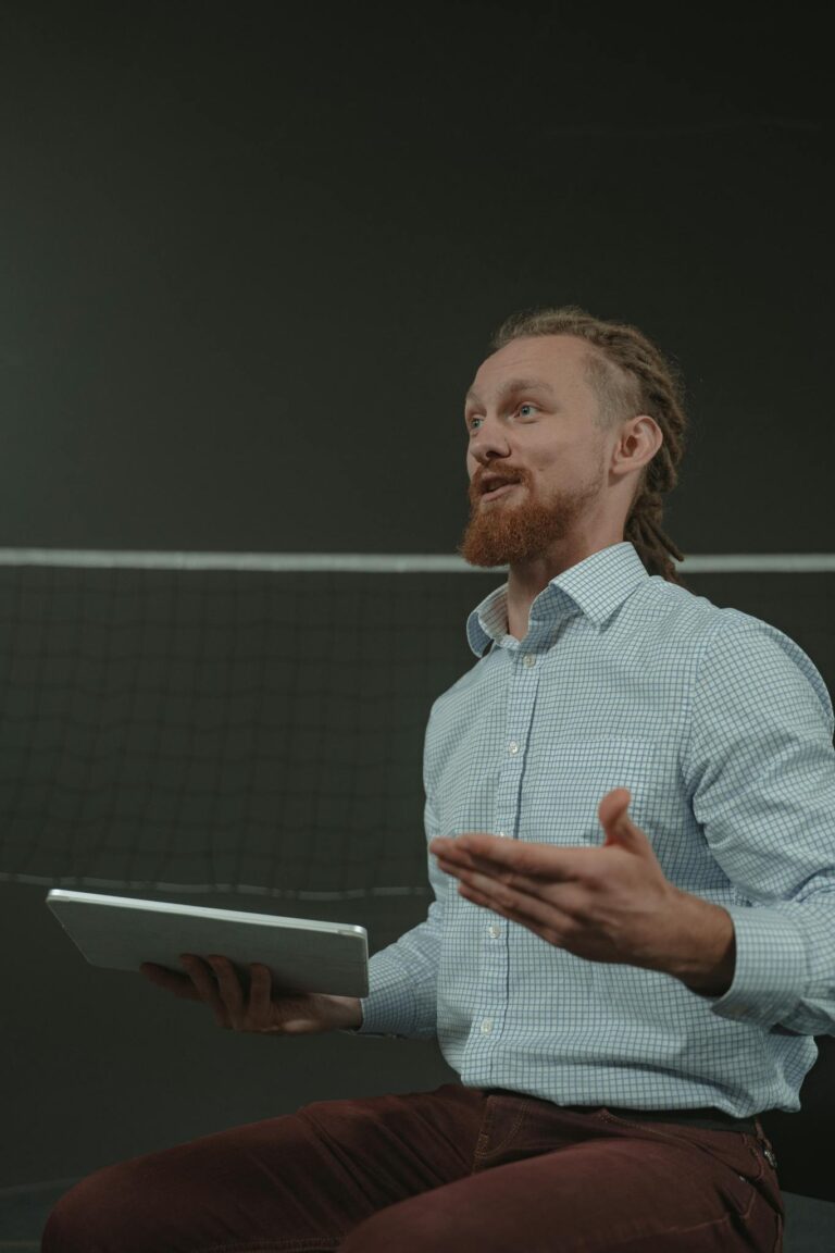 Business coach actively explaining concepts with a tablet in a professional setting.